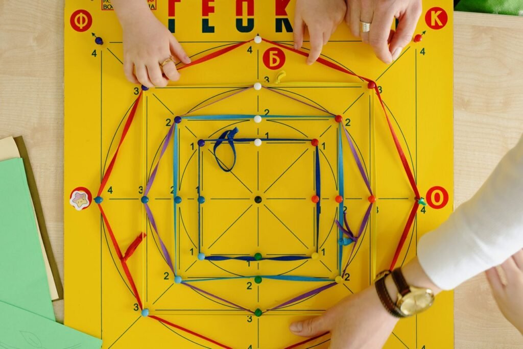 A close-up of adults and child playing an educational string game on a vibrant yellow board.
